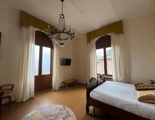 托迪Monastero SS. Annunziata的一间卧室配有一张床、两个窗户和吊灯