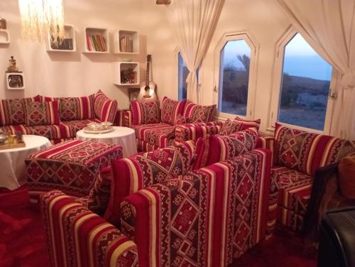 DouaïraRiad Sahara Sunset Beach Agadir的一间设有红色椅子和桌子及窗户的房间