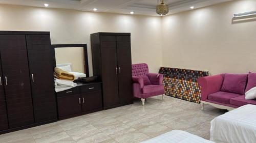 Al Qunfudhahنزل الخالدية的一间卧室配有紫色家具、镜子和紫色椅子