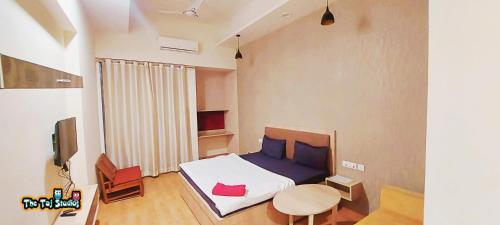 加济阿巴德Taj Suites & Studios-Top Place Couple Friendly Stay at Luxury Gaur City Mall #Movie, #Food Court #Shopping的一间卧室配有一张床、一张桌子和一台电视。