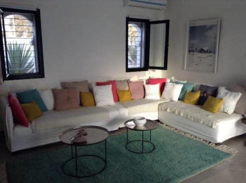 Al MaqārisahVilla Oasis de Luxe avec Piscine et Vue Panoramique的客厅配有带色彩缤纷枕头的白色沙发