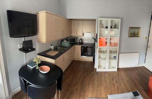 爱丁堡Edinburgh TWO BEDROOM apartment with free side street parking 24 hours的一间带桌子和冰箱的小厨房