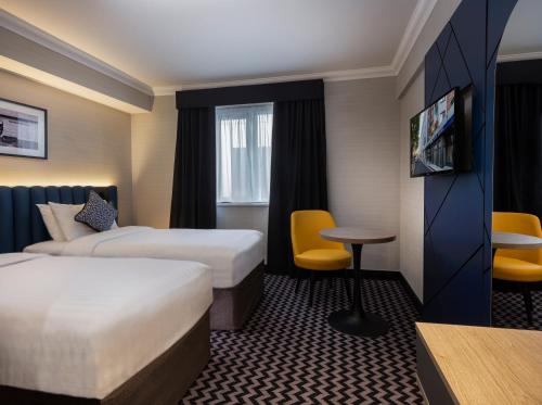 都柏林学院广场酒店的酒店客房设有两张床和一张桌子。