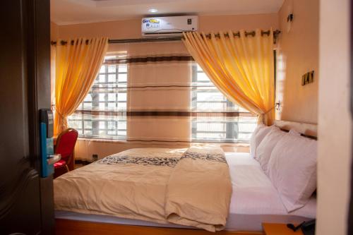 OjoDopad Hills Hotel and Suites的一间卧室设有床和黄色窗帘的窗户
