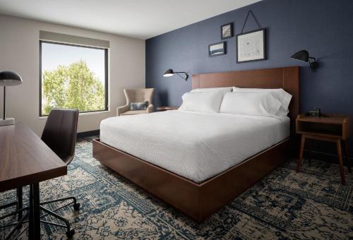 圣何塞Four Points by Sheraton San Jose Downtown的一间卧室配有一张床、一张书桌和一个窗户。