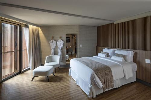 若昂佩索阿BA'RA Hotel的卧室配有一张白色大床和一把椅子
