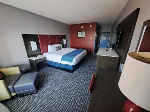 什里夫波特Del-Mar Airport Inn & Suites的配有一张床和一把椅子的酒店客房