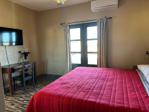 洛雷托Chulavista Loreto的一间卧室配有红色的床、一张书桌和一个窗户。