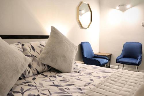 约克Priory Studio- New apartment inside the city walls的一张带枕头和两张蓝色椅子的床