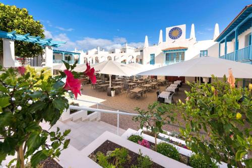 科拉雷侯Alua Suites Fuerteventura - All Inclusive的大楼前带桌子和遮阳伞的天井