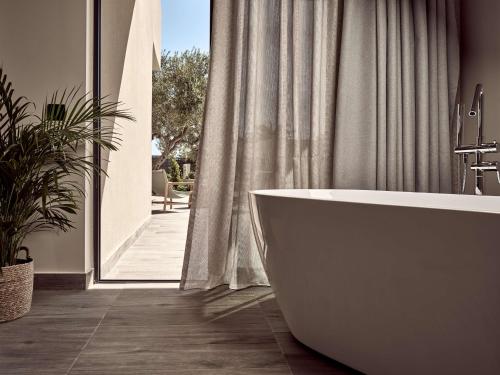 依拉佩特拉Numo Ierapetra Beach Resort Crete, Curio Collection Hilton的带浴缸的浴室和大窗户
