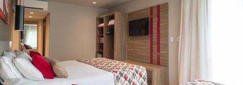格拉玛多Laghetto Stilo Borges - Apto 403B的卧室配有带红色枕头的白色床
