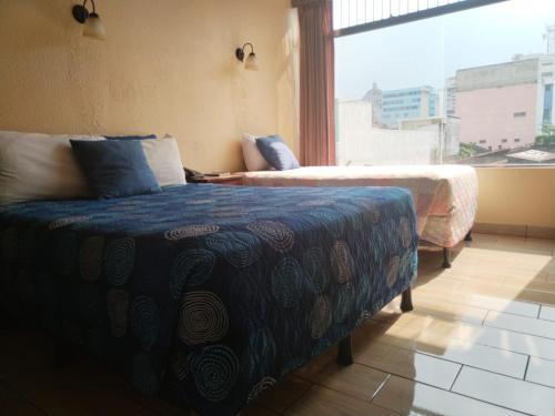 危地马拉塞维利亚酒店的一间卧室设有两张床和大窗户
