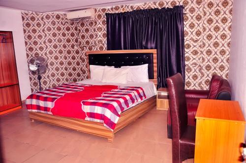 拉各斯Trending Place Hotel and Suites的一间卧室配有一张带红白毯子的床