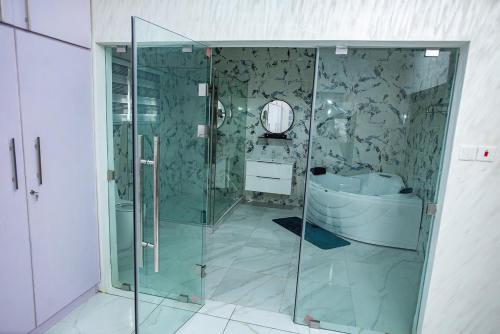 阿克拉Elegant and Cosy Four Bedroom Home in Accra的一间带玻璃淋浴和浴缸的浴室