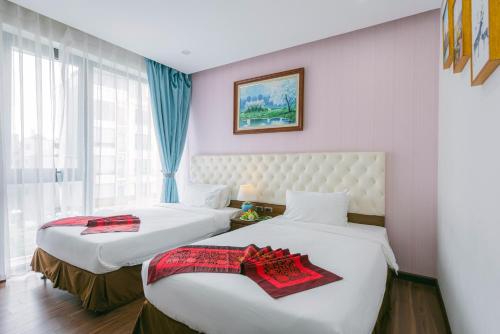 河内New Century Hotel Cau Giay的酒店客房设有两张床和窗户。