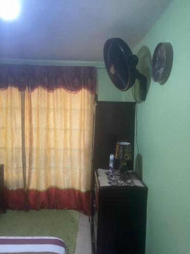 金斯敦Jamaican J Home的一间设有窗帘和一张桌子及窗户的房间