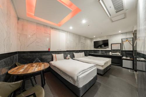 首尔Hotel Signature的一间卧室配有两张床、一张桌子和一台电视。