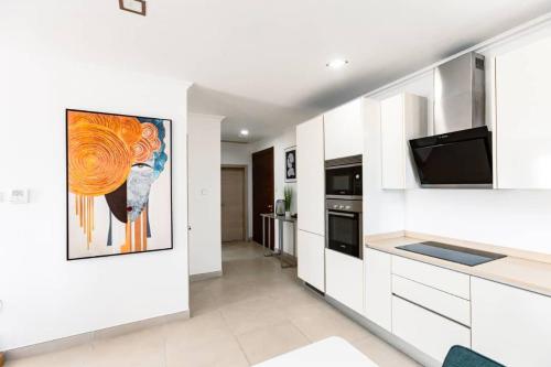 阿克拉Incredible luxurious 2 bedroom space Available的厨房配有白色橱柜,墙上挂有绘画作品