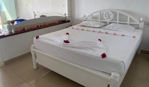 本托塔New Casamarc的一间卧室配有两张白色床,并装饰有红色的鲜花。