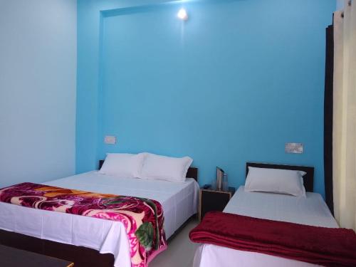 巴德里纳特Badrinath B V by prithvi yatra hotels的蓝色墙壁客房的两张床