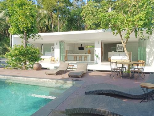 Ban NuaKPG Suite Dream的一个带椅子和桌子的游泳池以及一座房子