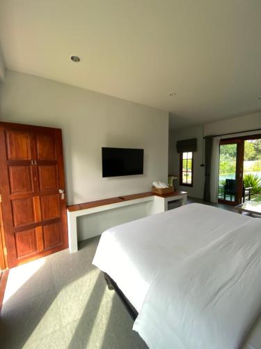 波普托Baan Yaimai Boutique Samui的卧室配有白色的床和平面电视。