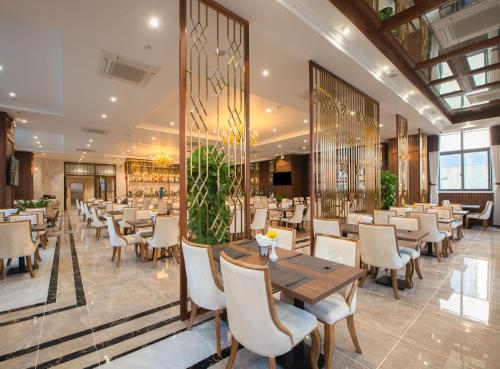 芽庄Daphovina Hotel的餐厅配有木桌和椅子