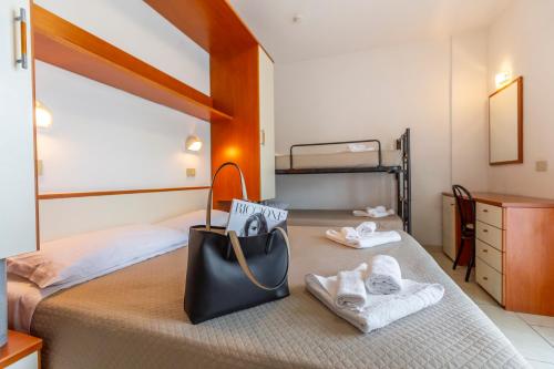 里乔内Hotel Luana的一间卧室,配有带毛巾和袋子的床