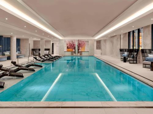 温莎Fairmont Windsor Park的酒店客房的大型游泳池配有椅子