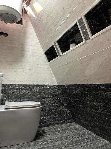 LerikLiki Home的浴室设有白色卫生间和黑色瓷砖。