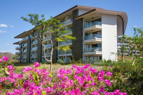 普拉卡海尔W Costa Rica Resort – Playa Conchal的公寓大楼前方有粉红色的鲜花