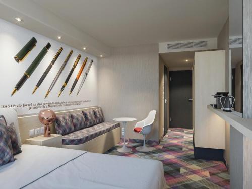 塞格德Science Hotel Prémium的酒店客房配有床、沙发和桌子。