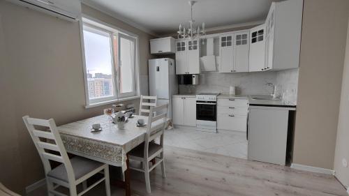 PrigorodnyyKamal Apart的厨房配有桌椅和白色冰箱。