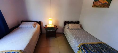 吉亚迪诺镇Casa V.Giardino pileta y cochera的一张桌子上灯的房间里两张床铺
