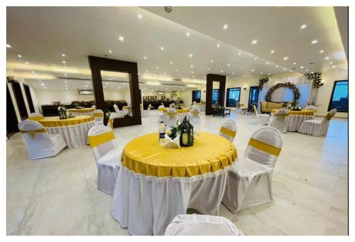 斯利那加Spring Vine Shrinagar的宴会厅配有黄色桌子和白色椅子