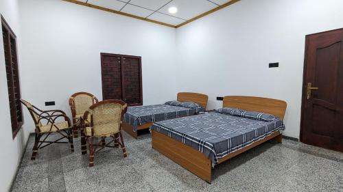 贾夫纳KATHIR Guest House的一间设有两张床和一张桌子及椅子的房间