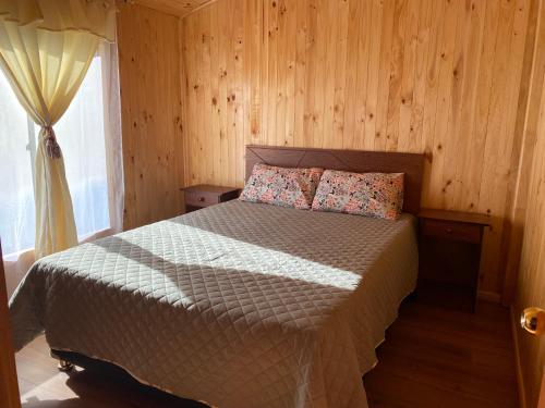 LiquiñeCabaña Llonquén的一间卧室配有一张带木墙和窗户的床。