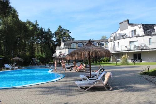波别罗沃Sunny Adventure Baltic Apartament的一个带椅子和遮阳伞的游泳池的度假酒店