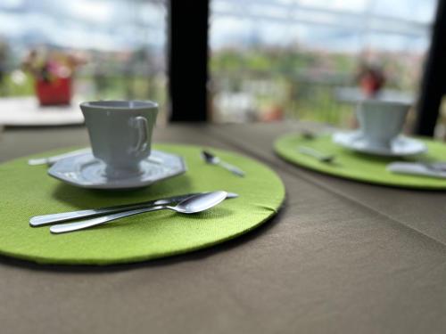 库尼亚Pitaya Suítes的两个绿盘,桌子上放有杯子和勺子
