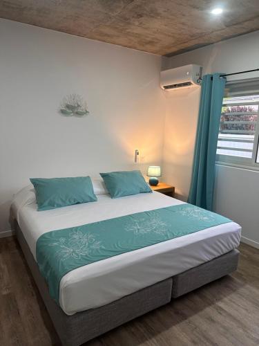 乌图罗阿Pension Irivai appartement "Uparu" 1 chambre bord de mer的一间卧室配有一张带蓝色枕头的大床