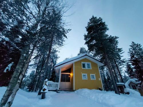 罗瓦涅米Lapland Forest Lodge的树林里的雪中的一个黄色小房子