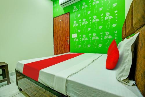 KurukshetraOYO Hotel Patiala的一间卧室配有一张带红色枕头的床和绿色的墙壁