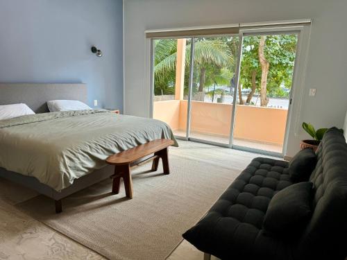 阿文图拉斯港Sasay的一间卧室配有一张床、一张沙发和一个大窗户