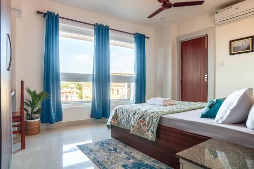 锡尔杰尔Borail Homes的一间卧室配有蓝色窗帘和大窗户