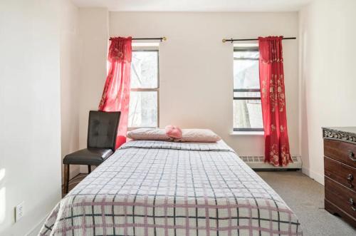 纽约Amazing 3BR 1Bath Apartment in NYC!的一间卧室配有一张床和一把椅子,还有两个窗户
