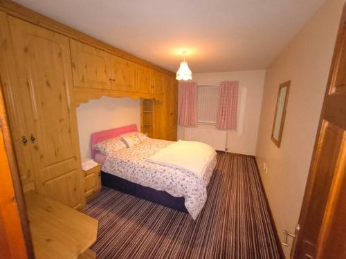 奥马Cosy 3 Bed Retreat in Omagh的一间卧室配有一张床和一个木制橱柜