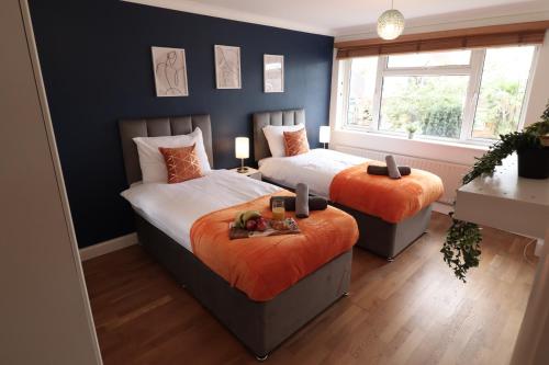 谢珀顿Perfect 2 Bedroom Flat Heathrow, Free Parking的一间卧室配有两张带橙色枕头的床