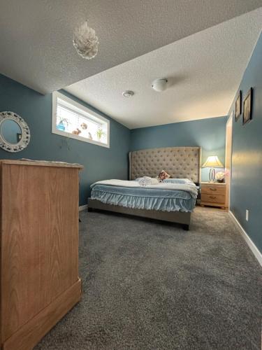 里贾纳Happy House - Regina City的一间卧室配有一张蓝色墙壁的床和一扇窗户