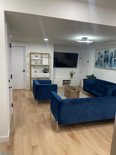 埃德蒙顿Stylish 2 Bedroom suite in SW Edmonton close to Windermere and Edmonton International Airport的客厅配有蓝色的沙发和平面电视。